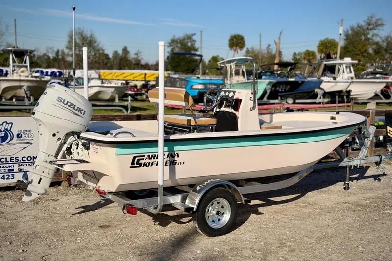 Slide: The Image of 2026 Carolina Skiff E16 JVX CC boat with Suzuki outboard motor on trailer. - 2