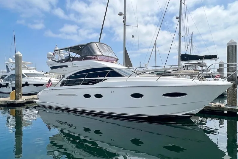 The Image of 2018 Princess F43 yacht docked in marina, reflecting on calm water under blue sky. - 0