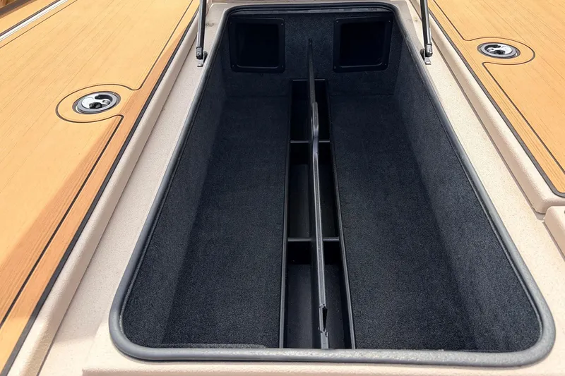 Slide: The Image of 2023 Avid 21 XB Elite boat storage compartment with carpeted interior and wooden deck. - 20