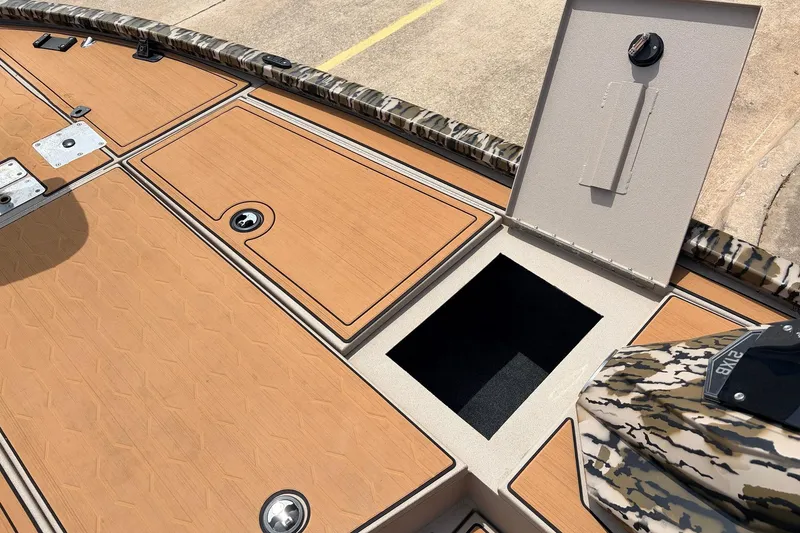 Slide: The Image of 2023 Avid 21 XB Elite boat deck with open storage compartment and camo accents. - 25
