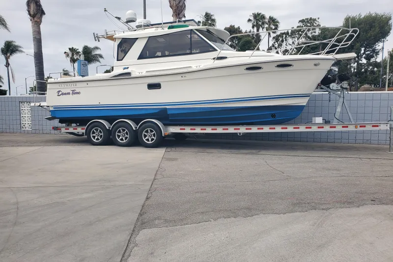 The Image of 2016 Cutwater 28 boat on trailer, parked outdoors with palm trees in background. - 0