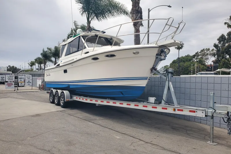 Slide: The Image of 2016 Cutwater 28 boat on trailer, parked outdoors near palm trees. - 14