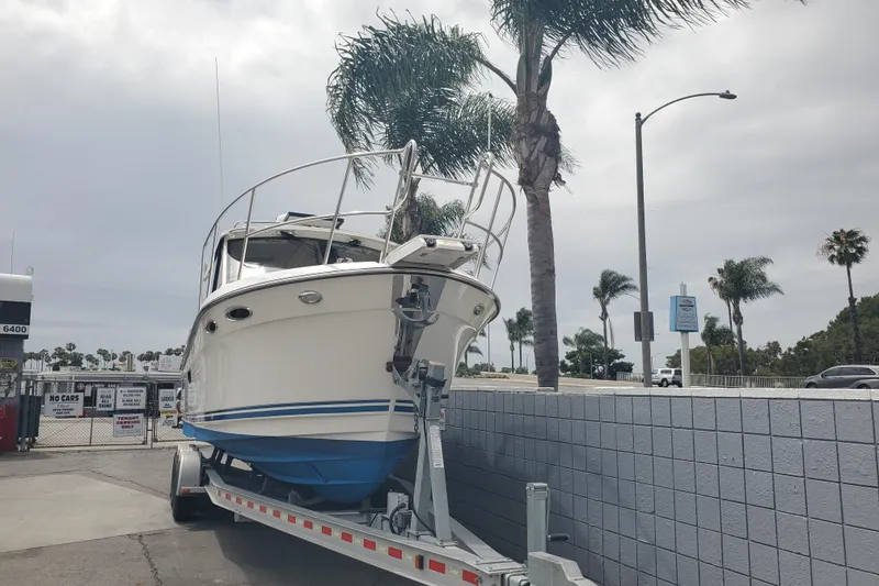 Slide: The Image of 2016 Cutwater 28 boat on trailer, parked near palm trees under cloudy sky. - 15