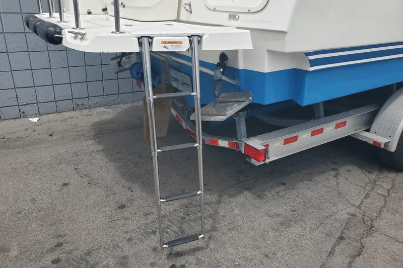 Slide: The Image of 2016 Cutwater 28 boat on trailer with ladder, blue and white hull, parked on concrete. - 17