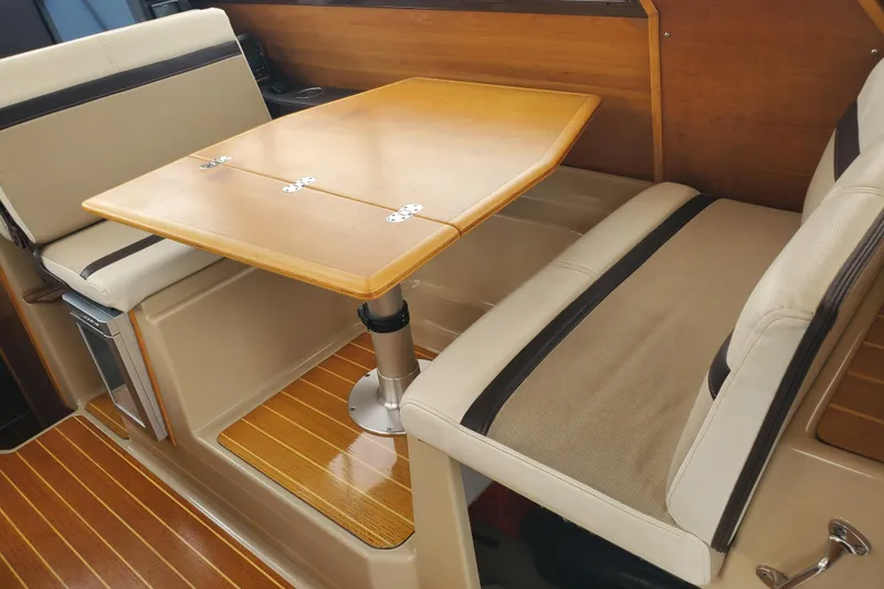 Slide: The Image of Interior of a 2016 Cutwater 28 boat with a wooden dining table and cushioned seating. - 4