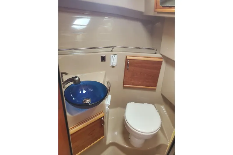 Slide: The Image of 2016 Cutwater 28 boat bathroom with blue sink, toilet, and wooden cabinetry. - 8
