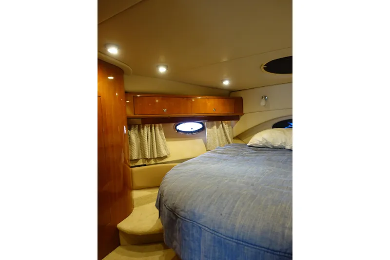 Slide: The Image of 2009 Regal Commodore 4460 yacht cabin with cozy bed, wooden cabinets, and porthole window. - 22
