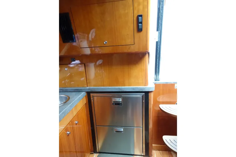 Slide: The Image of 2009 Regal Commodore 4460 yacht kitchen with wood cabinets and stainless steel fridge. - 25