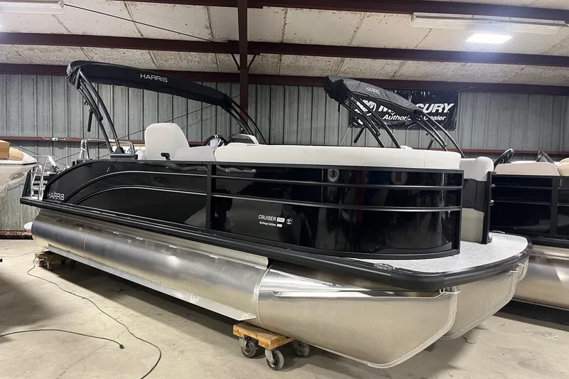 The Image of 2026 Harris Cruiser 210 SLDH pontoon boat in a showroom, featuring sleek black design. - 1