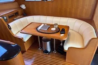 Slide: The Image of 2006 Ocean Alexander 48 Sedan interior with curved seating and wooden table. - 15