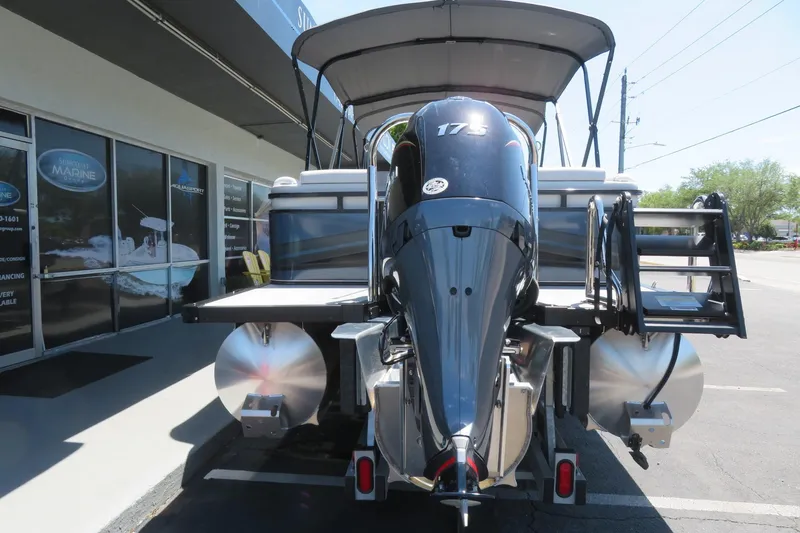 Slide: The Image of 2026 Avalon Venture 85 Quad Lounge boat with powerful outboard motor, parked outside showroom. - 11