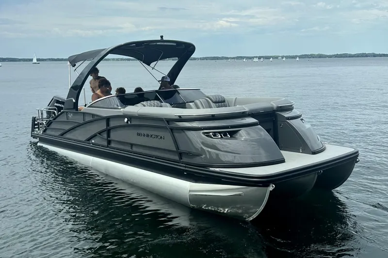 The Image of 2024 Bennington 25 QSBWA pontoon boat on a calm lake with passengers. - 1
