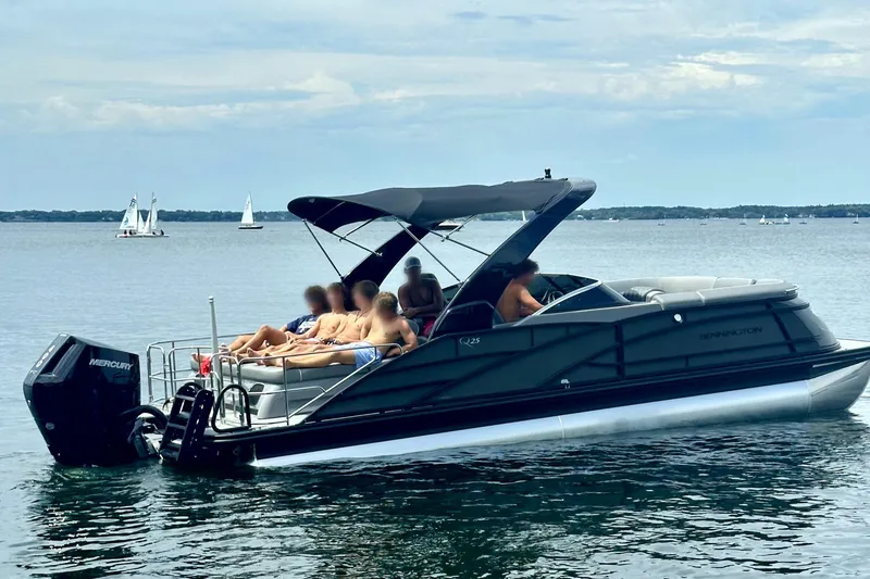 Slide: The Image of 2024 Bennington 25 QSBWA pontoon boat on a lake with passengers relaxing. - 14