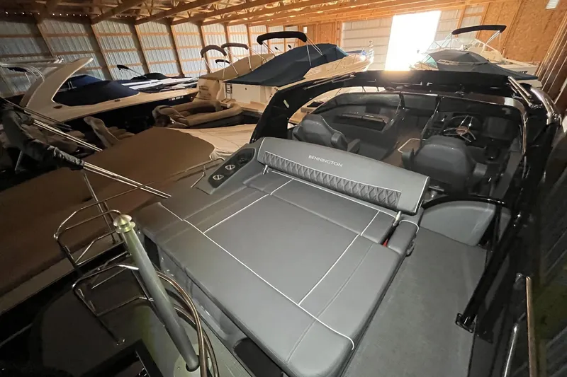 Slide: The Image of 2024 Bennington 25 QSBWA pontoon boat in storage, showcasing sleek design and spacious seating. - 28