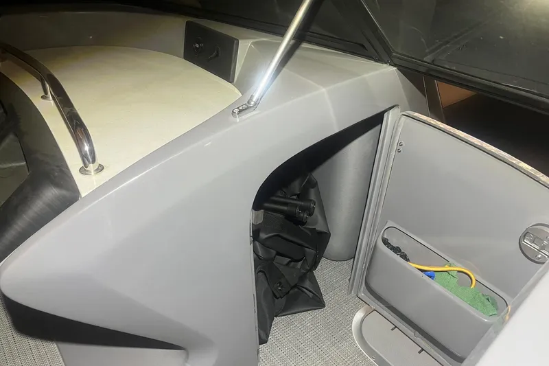 Slide: The Image of 2024 Bennington 25 QSBWA boat interior storage compartment with open door and accessories. - 38