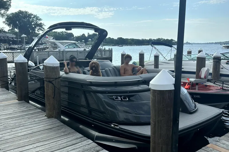 Slide: The Image of 2024 Bennington 25 QSBWA pontoon boat docked with passengers and a dog onboard. - 4