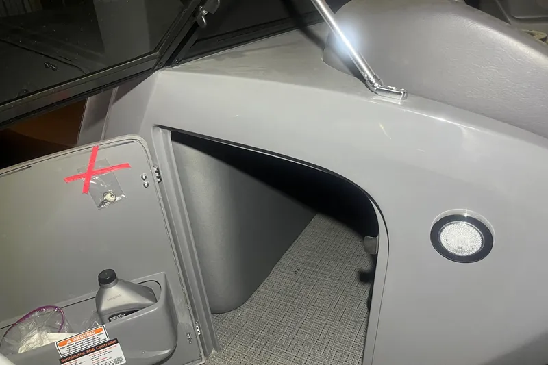 Slide: The Image of 2024 Bennington 25 QSBWA boat interior storage compartment with open door and accessories. - 49