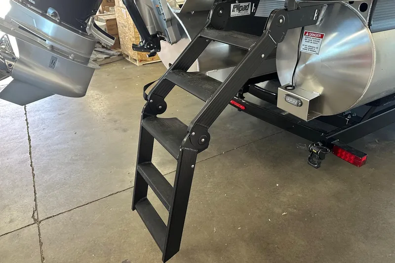 Slide: The Image of 2024 Bennington 25 QSBWA boat with foldable boarding ladder and motor, in a garage setting. - 6