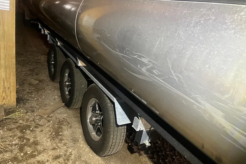 Slide: The Image of 2024 Bennington 25 QSBWA pontoon boat on trailer, close-up view of wheels and hull. - 61
