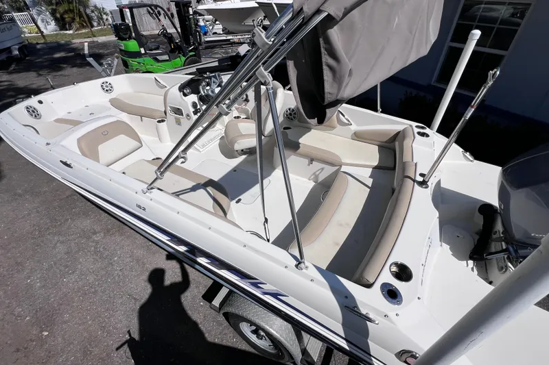 Slide: The Image of 2017 Stingray 182 SC boat with beige seating and canopy, parked outdoors. - 11