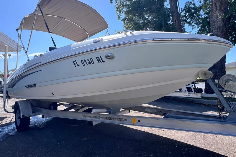 Slide: The Image of 2017 Stingray 182 SC boat on trailer with canopy, parked outdoors. - 2