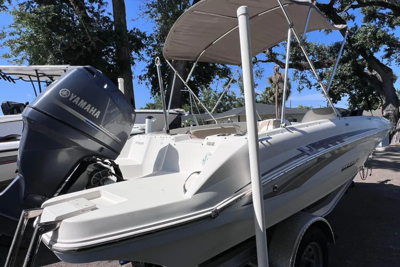 Slide: The Image of 2017 Stingray 182 SC boat with Yamaha outboard motor, parked outdoors under a canopy. - 7