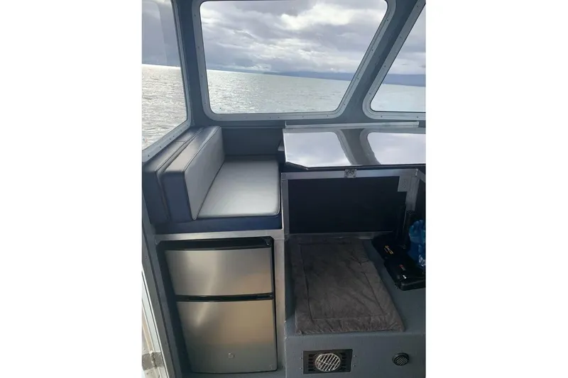 Slide: The Image of Interior of 2021 Custom Aluminum Crabber boat with seating and mini fridge, overlooking the ocean. - 5