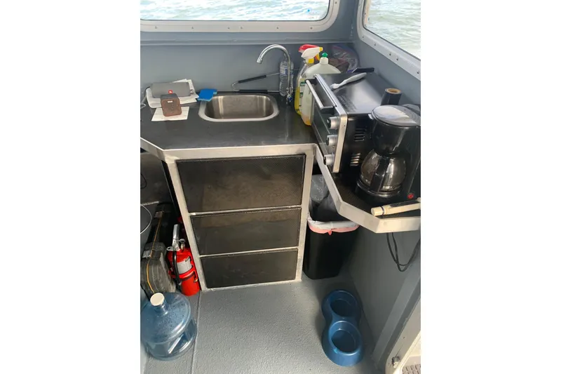 Slide: The Image of Compact kitchen area on 2021 Custom Aluminum Crabber boat with sink, coffee maker, and storage. - 7