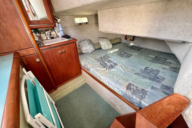 Slide: The Image of 1988 Bayliner 3218 Motoryacht cabin with bed, wooden cabinetry, and compact sink area. - 13
