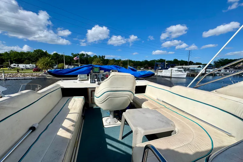 Slide: The Image of 1988 Bayliner 3218 Motoryacht interior with seating, helm, and marina view under blue sky. - 14