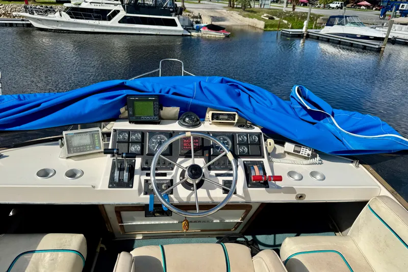 Slide: The Image of 1988 Bayliner 3218 Motoryacht helm with navigation equipment and blue cover, docked at marina. - 15
