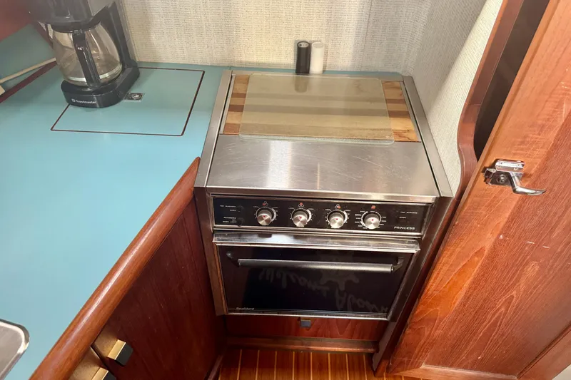Slide: The Image of 1988 Bayliner 3218 Motoryacht kitchen with stove, coffee maker, and wooden cabinetry. - 8