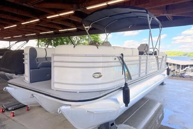 The Image of 2019 Veranda VP25RC pontoon boat under a wooden canopy, featuring white seating and a black canopy. - 0