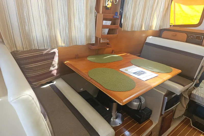 Slide: The Image of Interior of 2014 Ranger Tugs R-27 with dining area, wooden table, and striped curtains. - 11