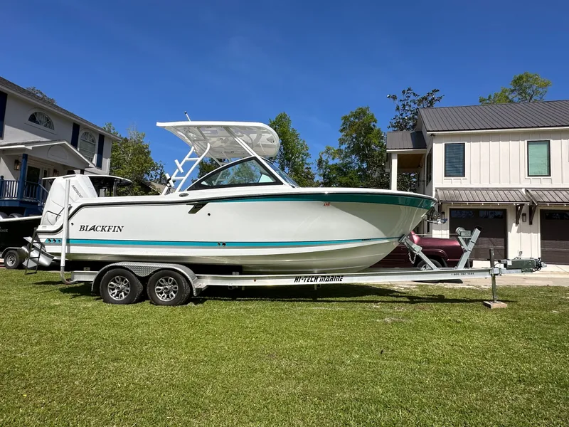 Slide: The Image of 2024 Blackfin 252 DC boat on trailer in front of house. - 0