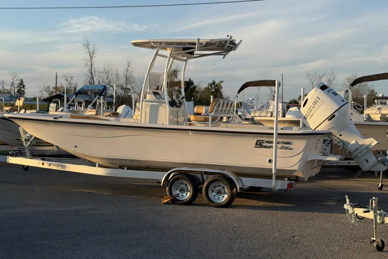 Slide: The Image of 2026 Carolina Skiff 23 LS boat on trailer, parked outdoors, with Suzuki outboard motor. - 2