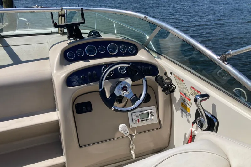 Slide: The Image of Cockpit of 2002 Sea Ray Sundancer 260 with steering wheel and control panel by the water. - 14