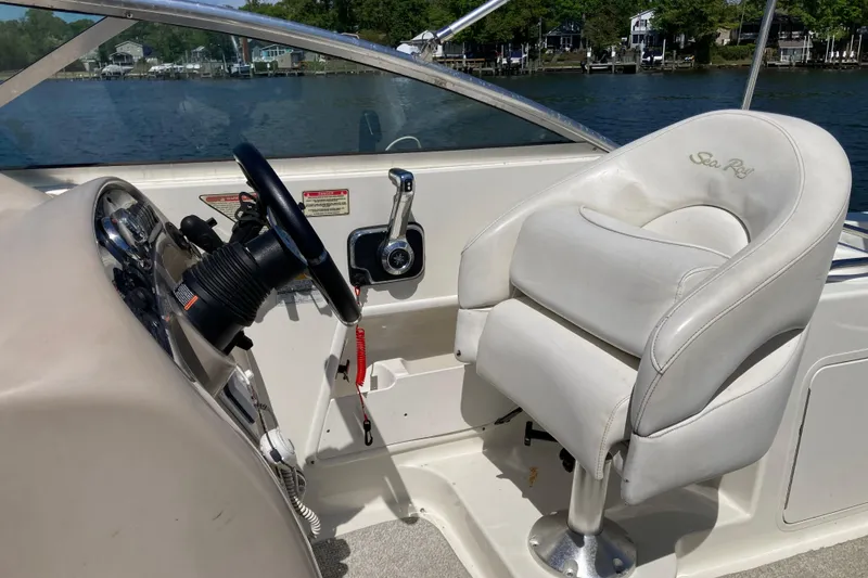 Slide: The Image of Captain's seat and helm of a 2002 Sea Ray Sundancer 260 boat, overlooking a serene waterway. - 18