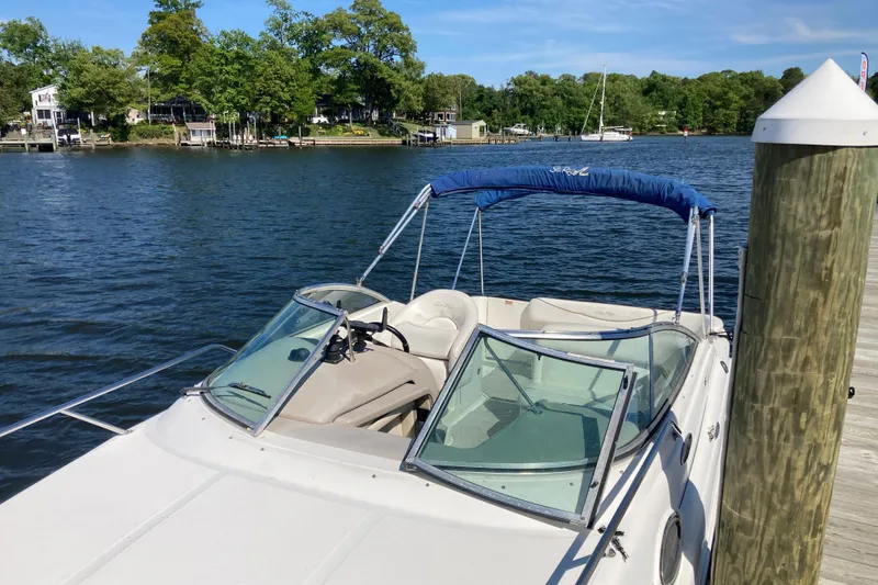 Slide: The Image of 2002 Sea Ray Sundancer 260 docked by a scenic waterfront with trees. - 2