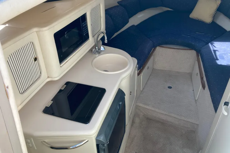 Slide: The Image of Interior of 2002 Sea Ray Sundancer 260, featuring kitchenette and cozy seating area. - 32