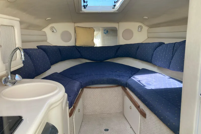 Slide: The Image of Interior of 2002 Sea Ray Sundancer 260 with blue cushioned seating and compact kitchenette. - 33