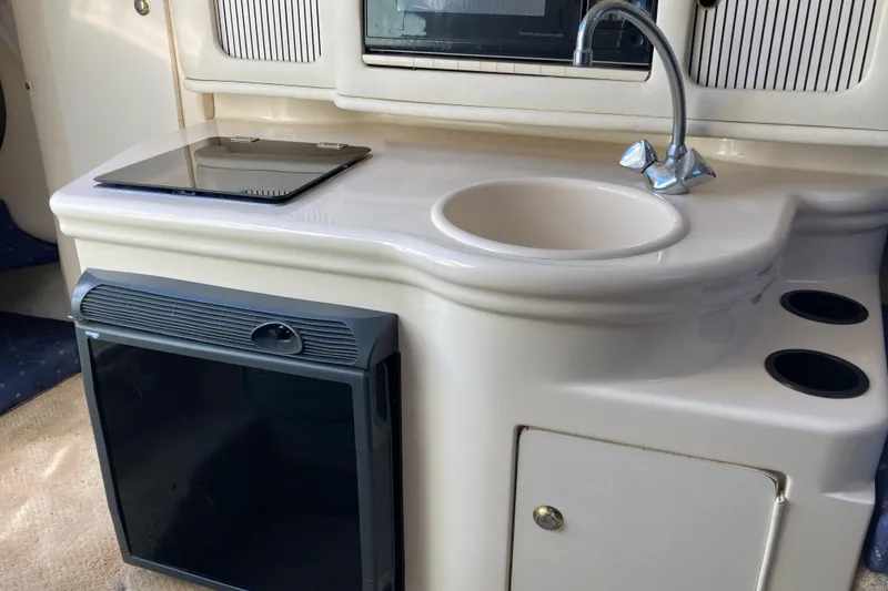 Slide: The Image of Interior of a 2002 Sea Ray Sundancer 260, featuring a compact kitchenette with sink and stove. - 36