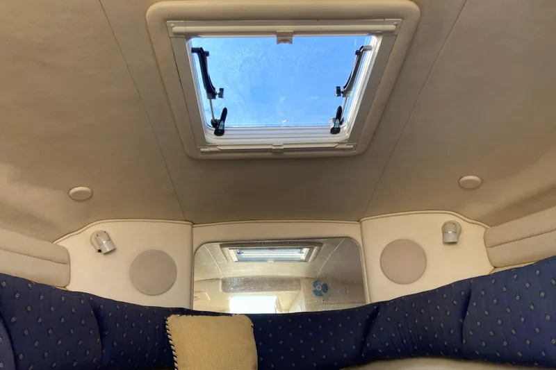 Slide: The Image of Interior cabin view of a 2002 Sea Ray Sundancer 260 with skylight and blue seating. - 43