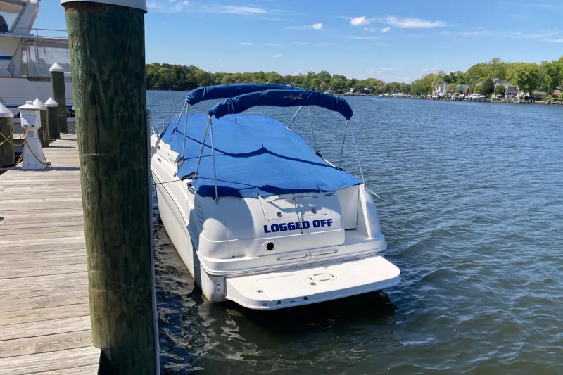 Slide: The Image of 2002 Sea Ray Sundancer 260 boat docked with blue cover, named "Logged Off". - 54
