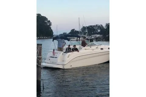 Slide: The Image of 2002 Sea Ray Sundancer 260 boat docked on a calm waterway with passengers onboard. - 7