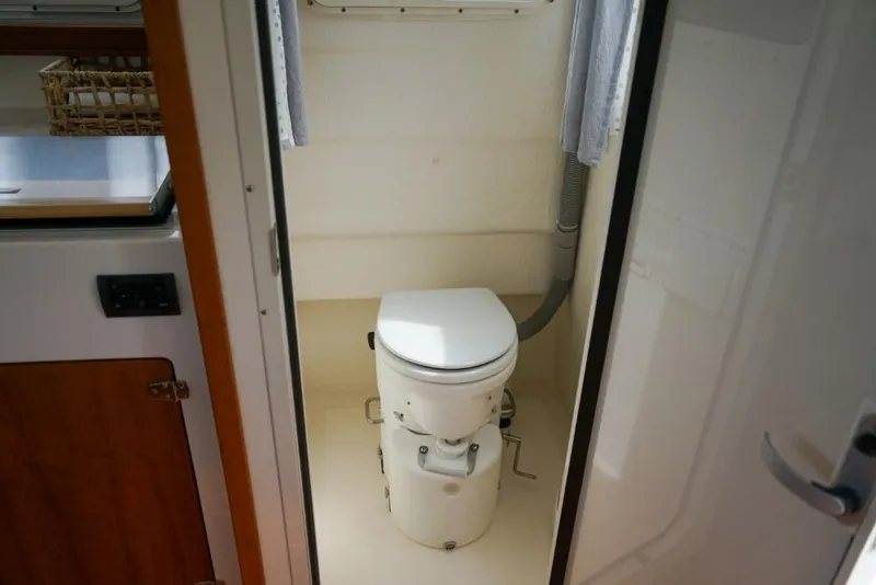 Slide: The Image of 2018 C-Dory 25' Tomcat Catamaran interior bathroom with compact marine toilet. - 11