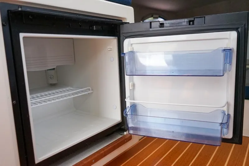Slide: The Image of Open refrigerator inside 2018 C-Dory 25' Tomcat Catamaran, showcasing interior storage space. - 19