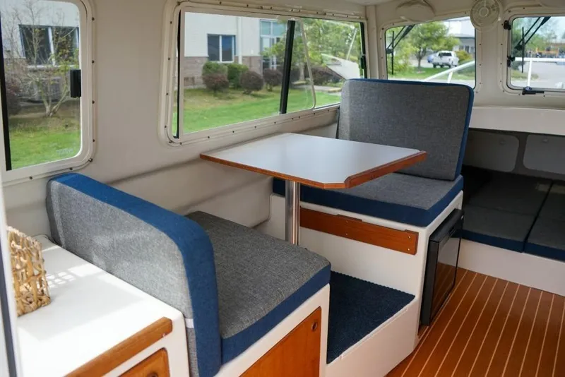 Slide: The Image of Interior of 2018 C-Dory 25' Tomcat Catamaran with seating and table, featuring wood accents. - 9