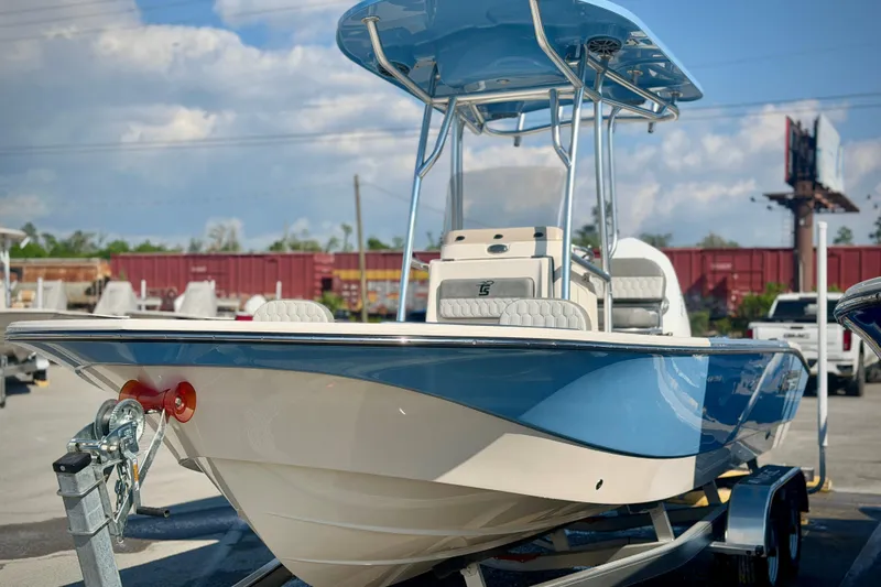 Slide: The Image of 2026 Carolina Skiff 22 Ultra Elite boat with blue hull and T-top in a marina setting. - 2