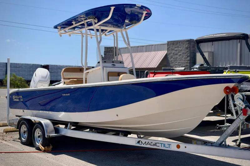 The Image of 2026 Carolina Skiff 24 Ultra Elite boat on trailer, blue and white design. - 0
